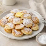 Poffertjes Rezept mit Butter und Puderzucker auf einem hellen Teller